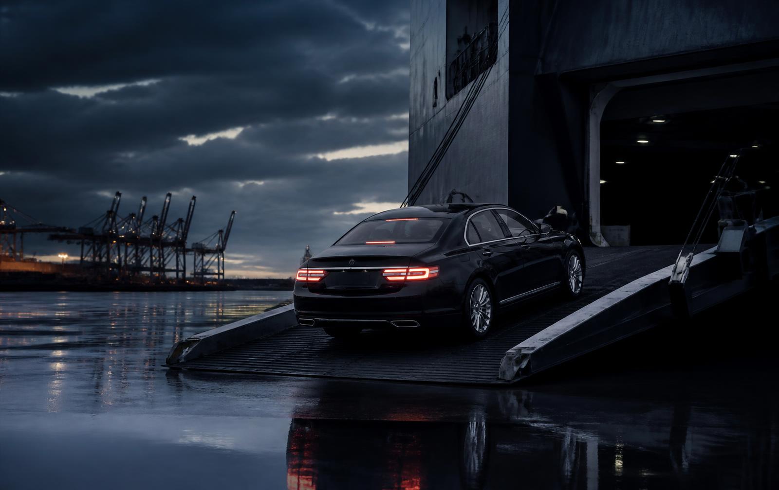 Dark luxury sedan driving onto a car carrier vessel at a port